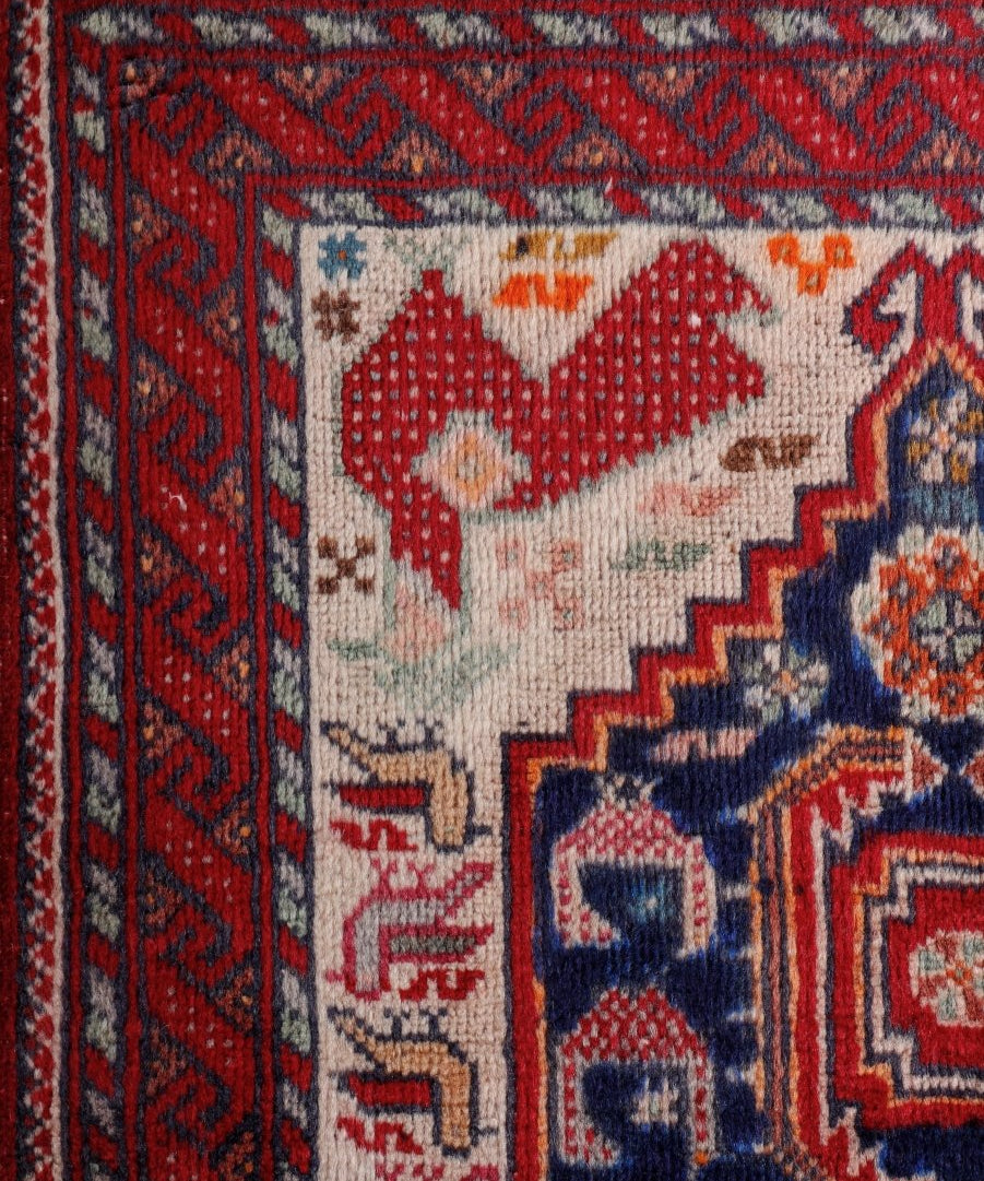 Persian Baluch runner rug corner detail with red and navy motifs on cream