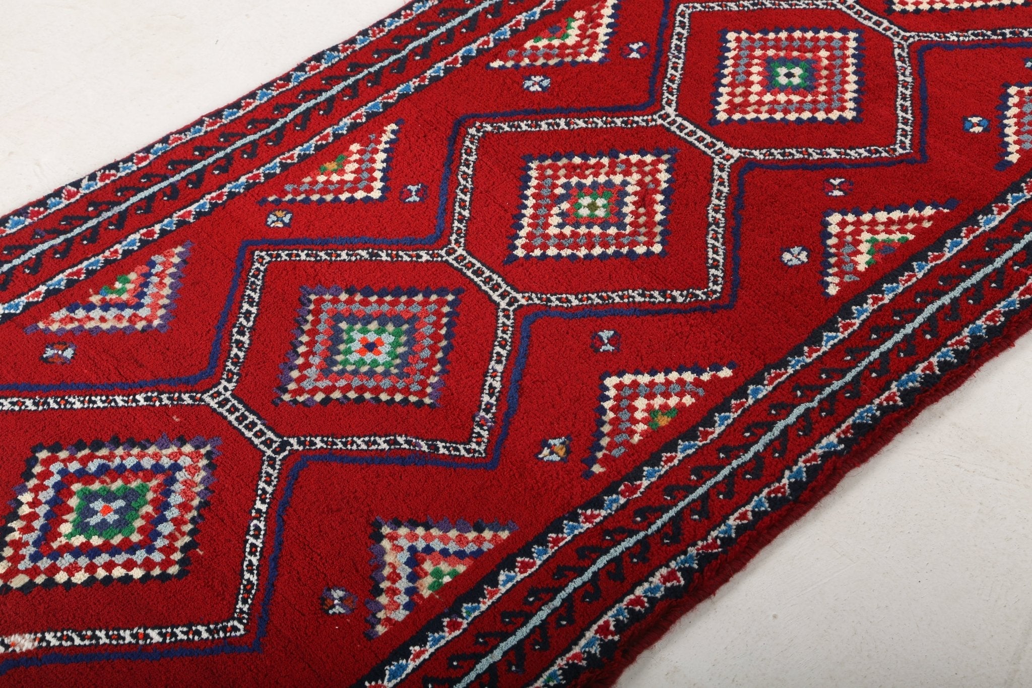 Persian Baluch runner rug edge detail with repeated square medallions in red