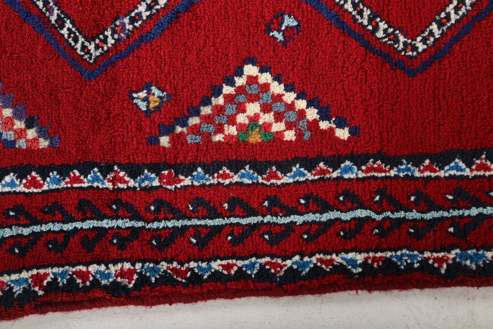 Persian Baluch runner rug border with red field, blue stripe trim, and diamond motifs