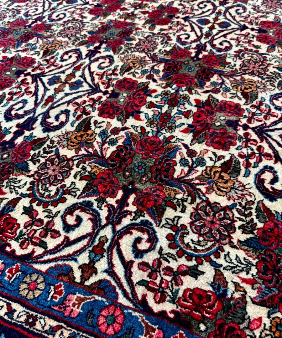 Bidjar-style rug close-up with ornate ivory, red, and navy scrollwork and rosette blooms