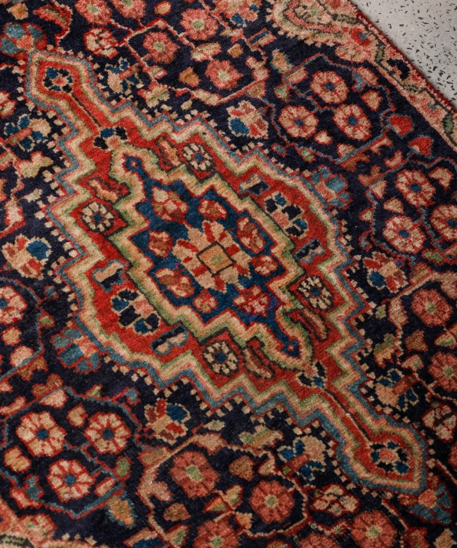 Persian Bidjar rug close-up with navy background, red-orange accents, and diamond motifs