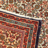 Persian Bidjar rug border close-up with red panel, navy trim, and geometric guard stripes.