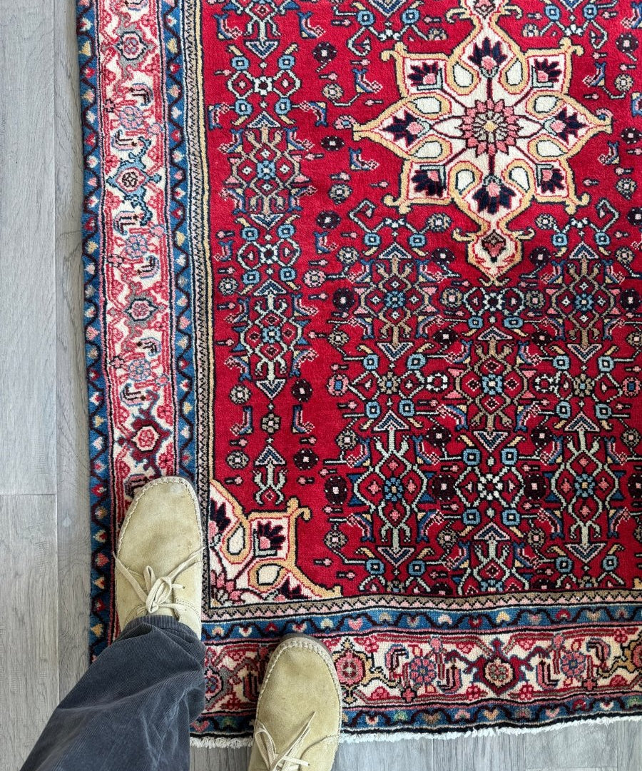Persian Bidjar rug with red field, cream medallion, and blue border pattern.