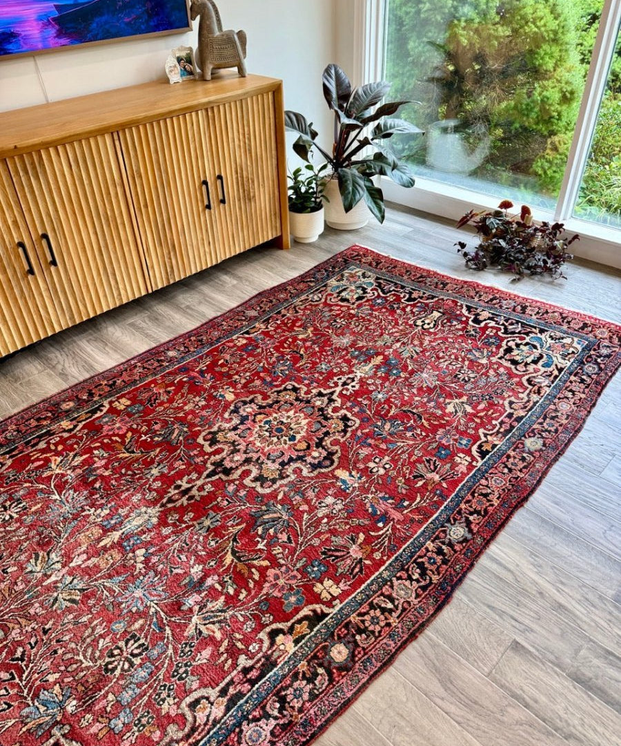 Red Persian Bidjar rug in living room with ornate floral pattern and dark border.