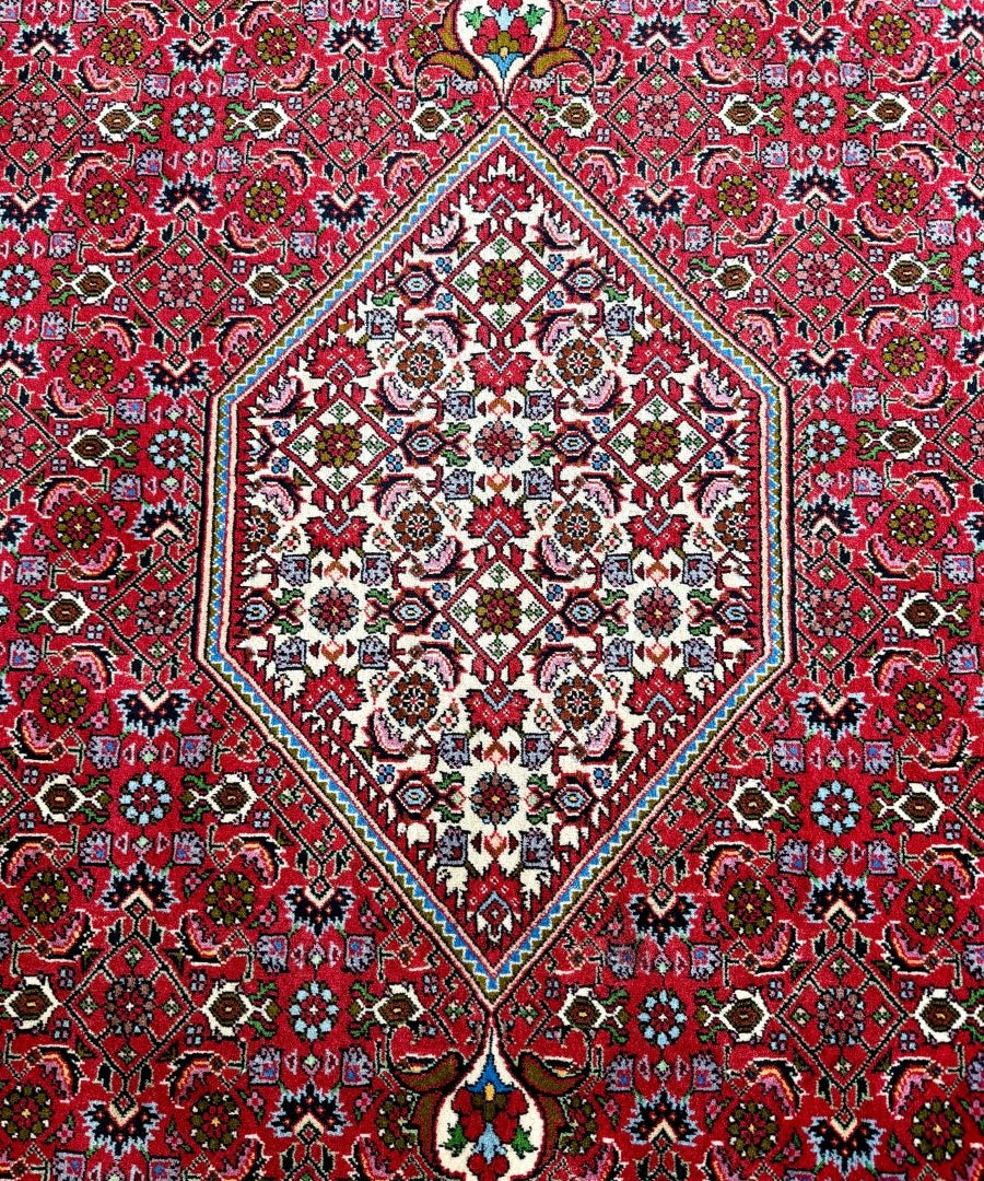 Red Bidjar-style rug close-up with diamond medallion, teal accents, and floral details