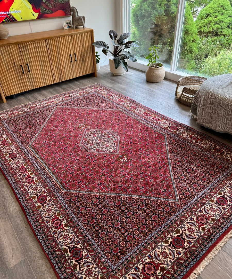 Red Persian-style Bidjar area rug laid out in a living room with ornate center medallion