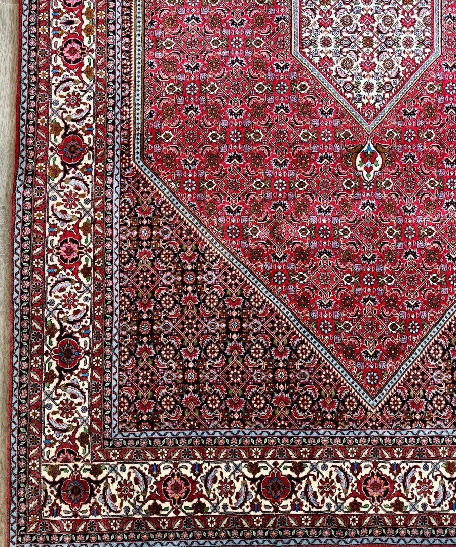 Red Persian-style Bidjar area rug with central medallion, geometric border, and corner motifs