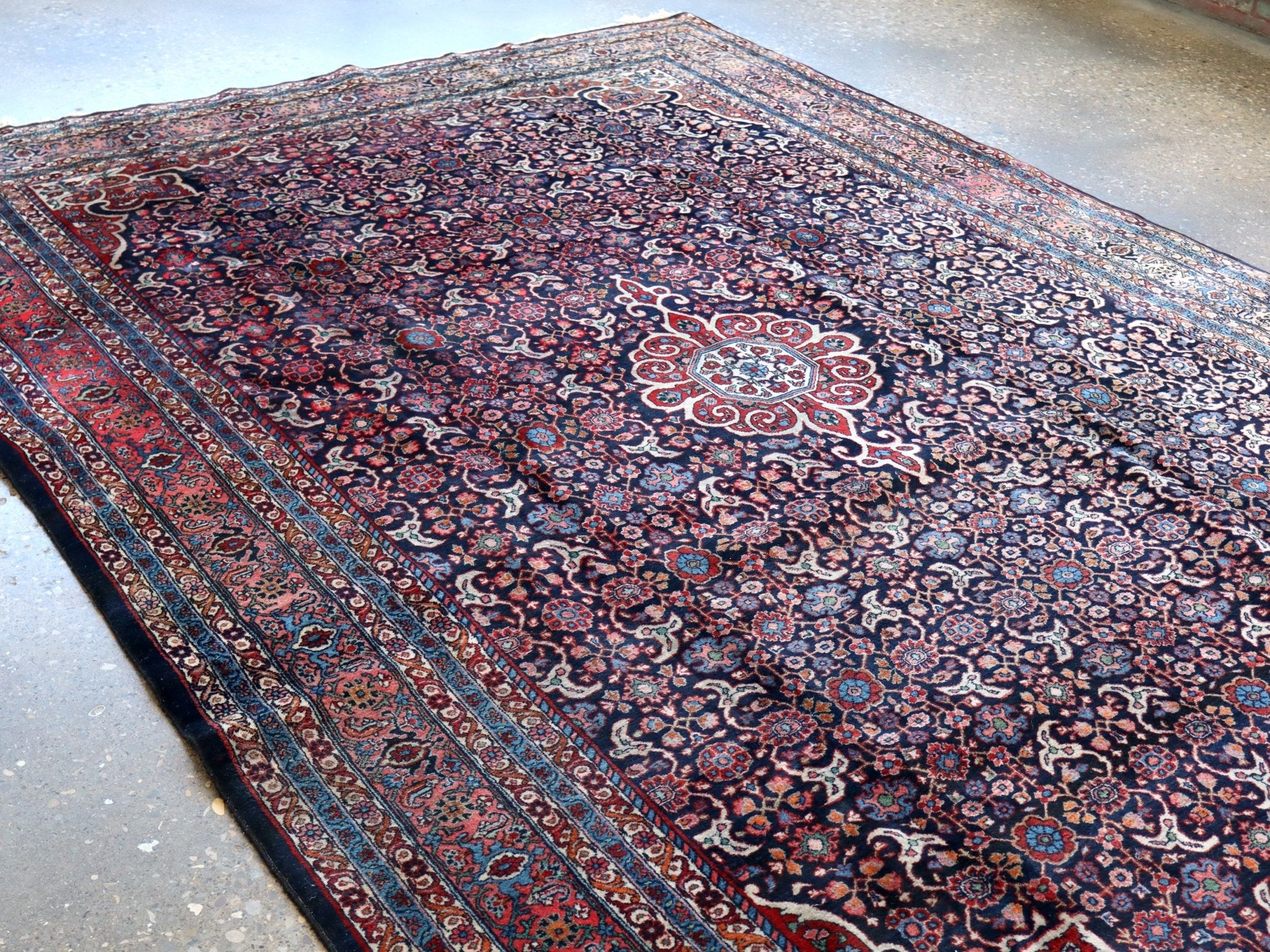 Persian-style area rug with navy, red, and cream medallion floral pattern and border