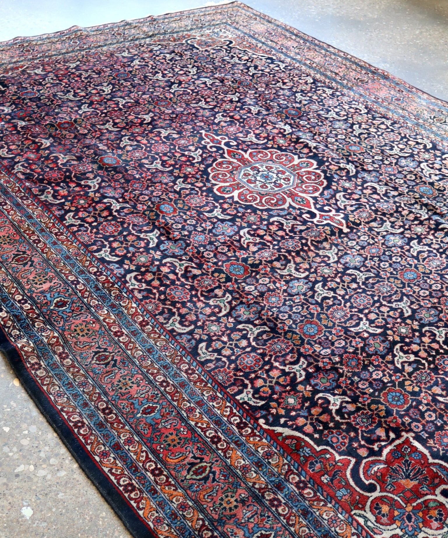 Persian-style area rug showing central medallion and ornate navy-red floral border