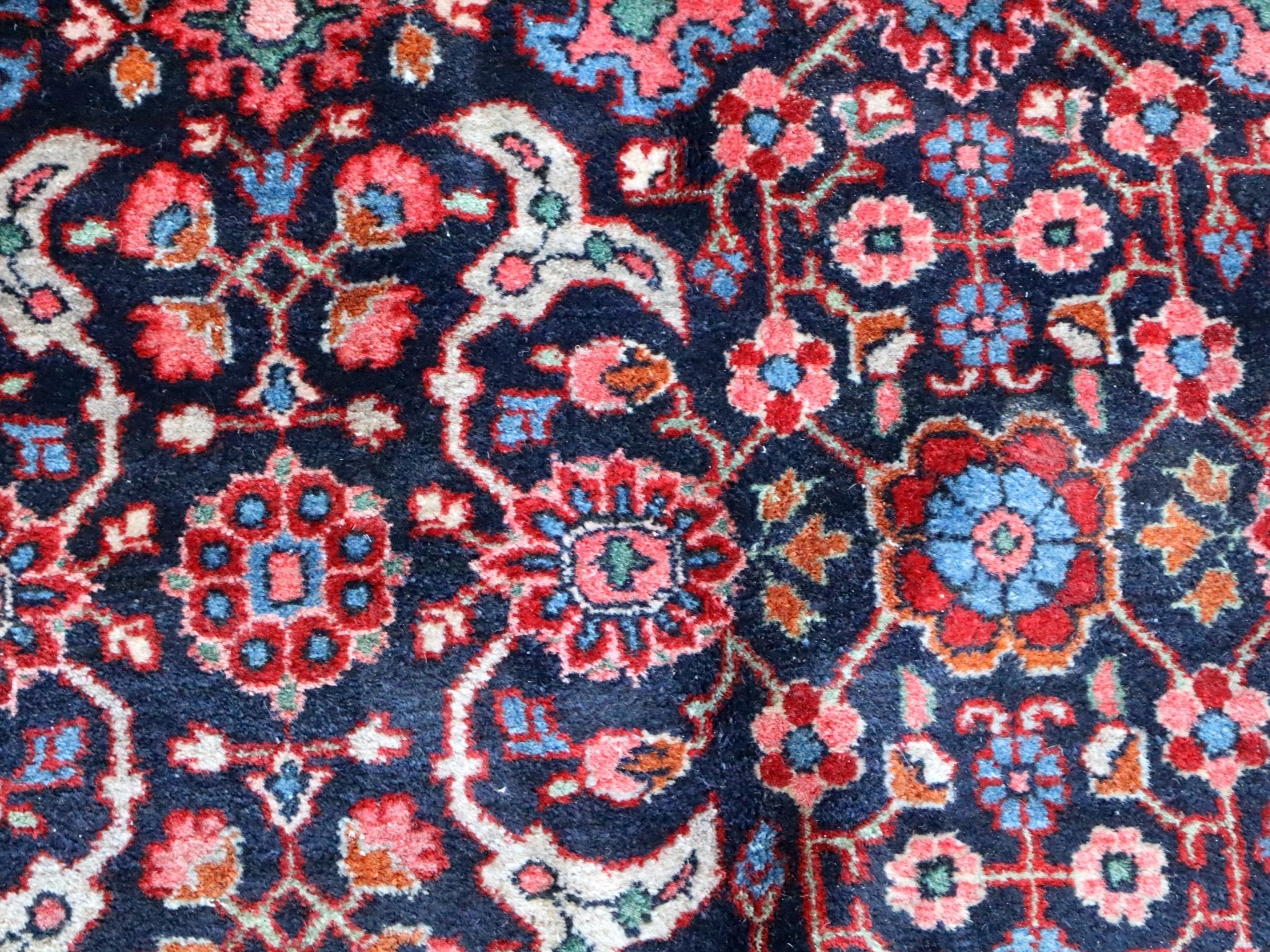 Persian-style rug close-up with red, blue, and cream floral lattice pattern