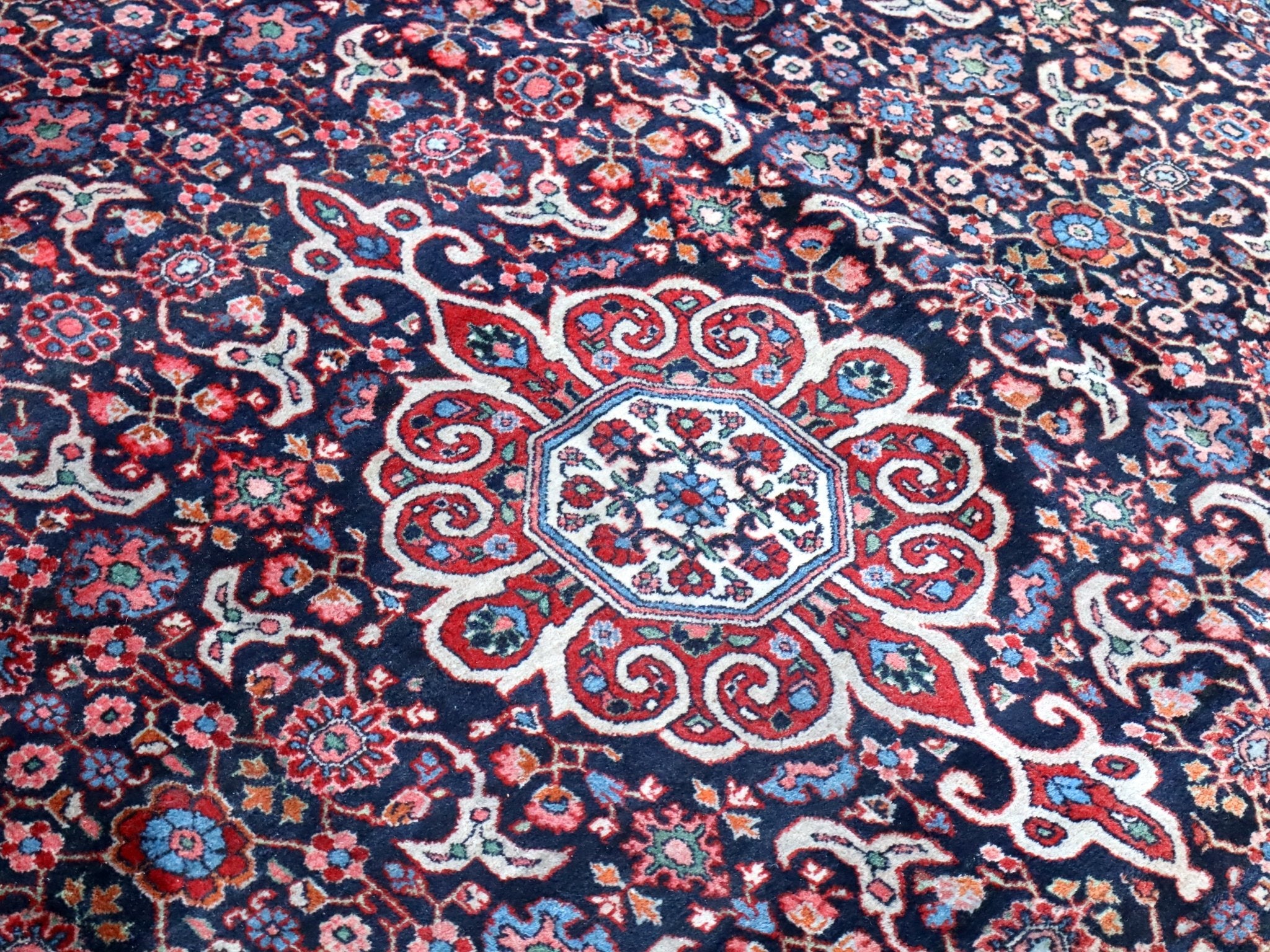 Persian-style rug detail of cream rosette medallion surrounded by red and blue florals