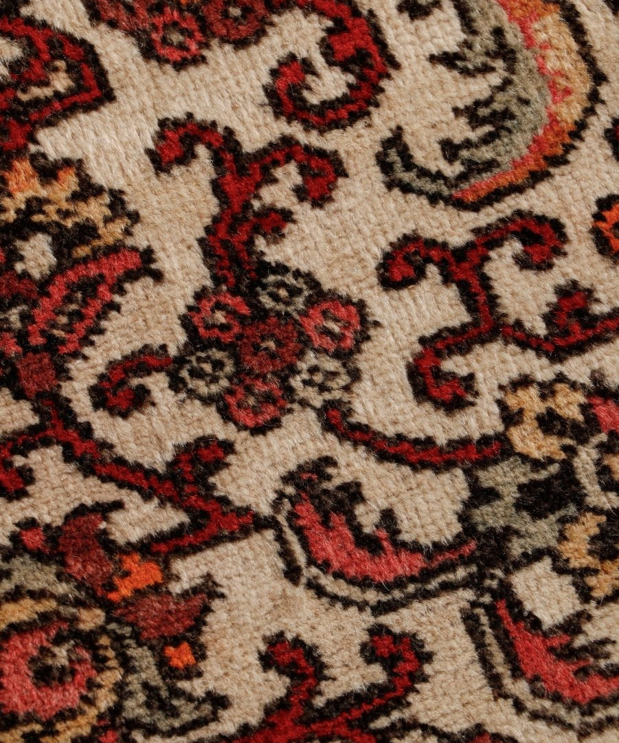 Persian Bidjar runner rug detail: cream texture with red, black, and dark accent floral motifs.