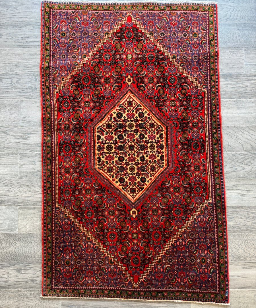 Persian Bijar rug with red center medallion and ornate blue-black motifs