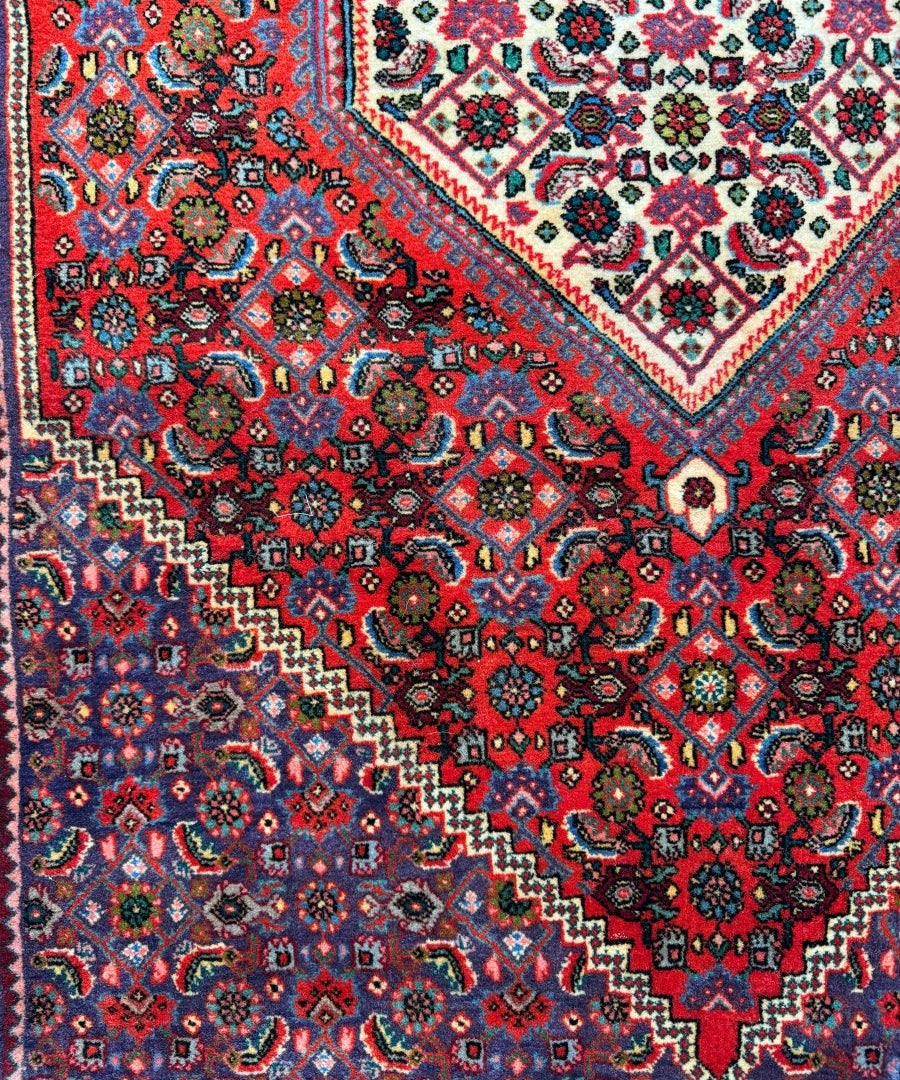 Persian Bijar rug close-up of red, blue, and cream floral medallion pattern