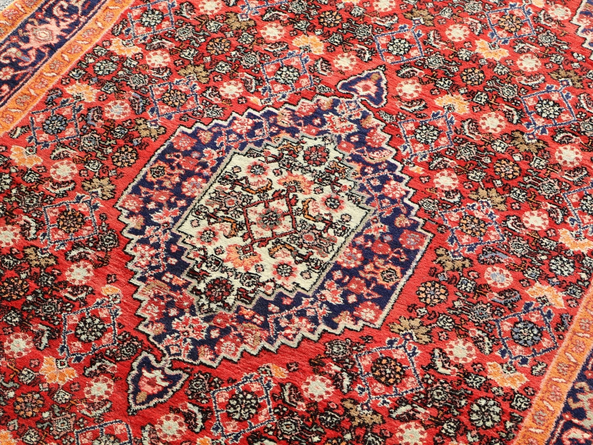 Persian Bijar rug close-up with red, blue, and cream diamond motifs