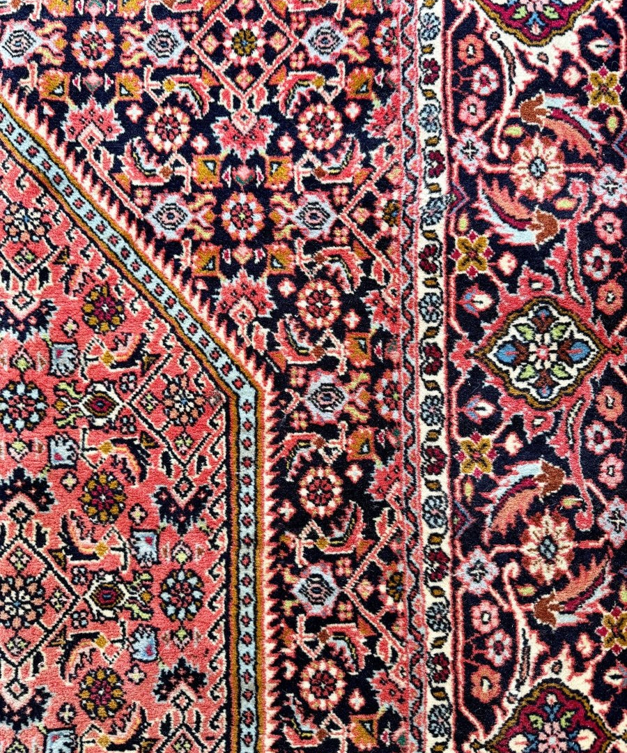 Close-up of red Persian rug pattern with floral medallions, dark navy accents, border