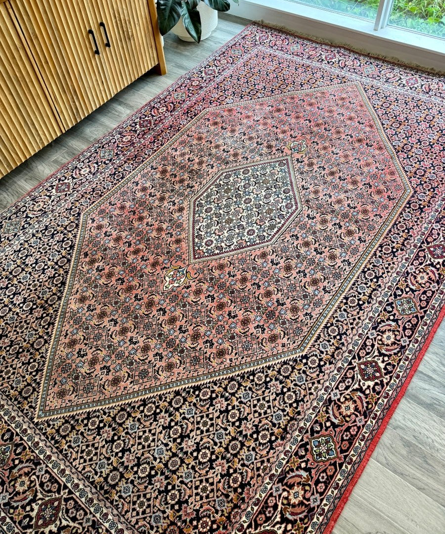 Red Persian rug with blue and cream medallion, ornate corner motifs, thin border