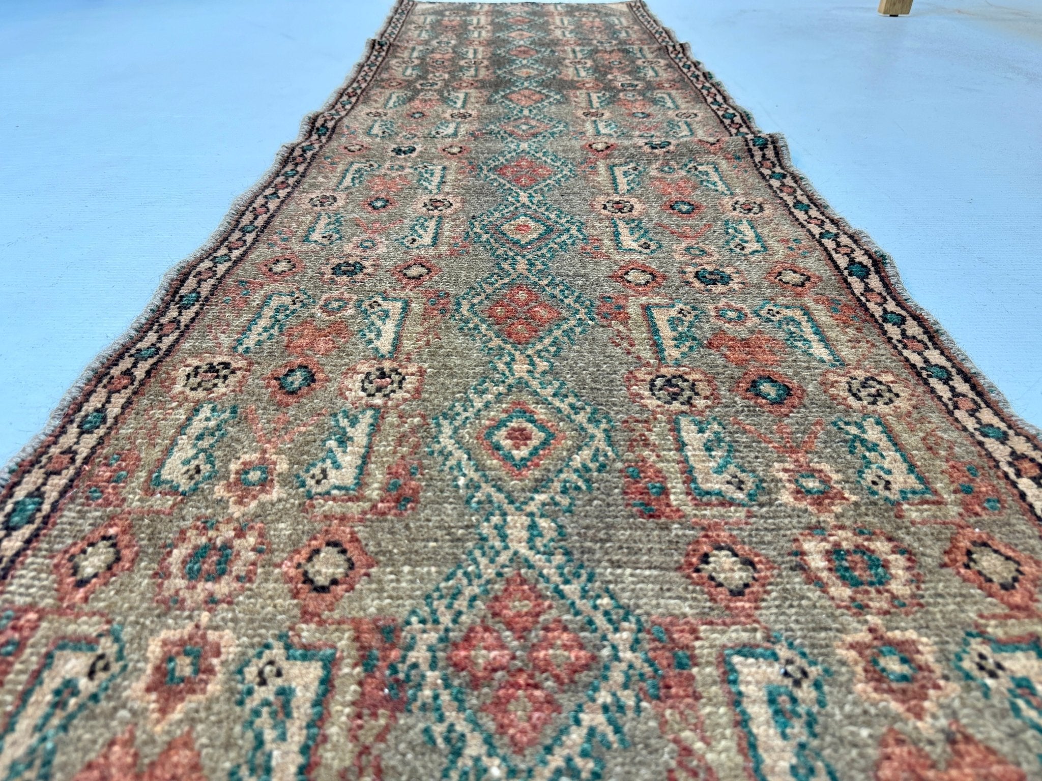 Persian Borujerd runner rug textured beige field with turquoise and rust motif rows