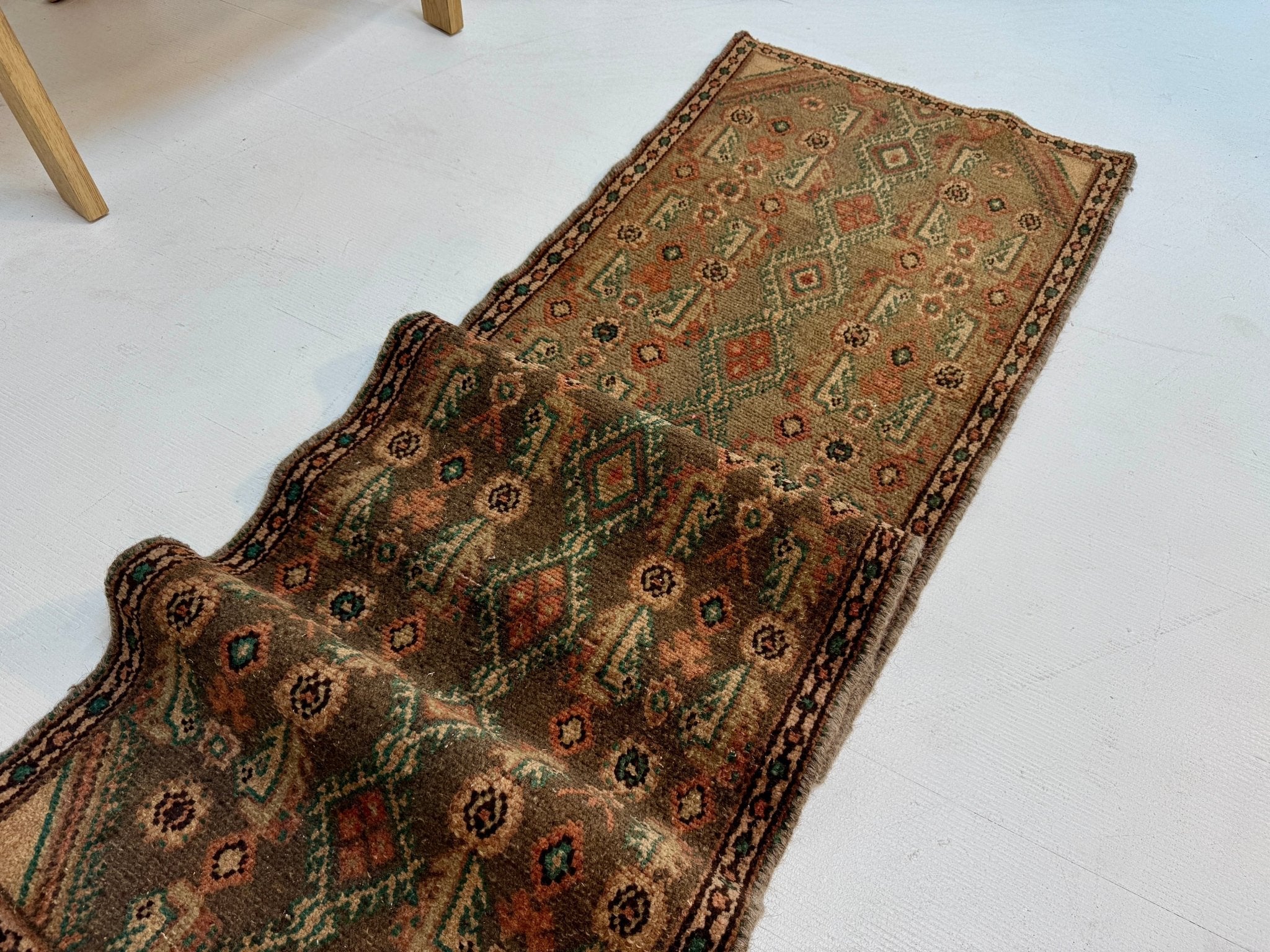 Persian Borujerd runner rug angled view with warm brown, teal and orange patterned bands