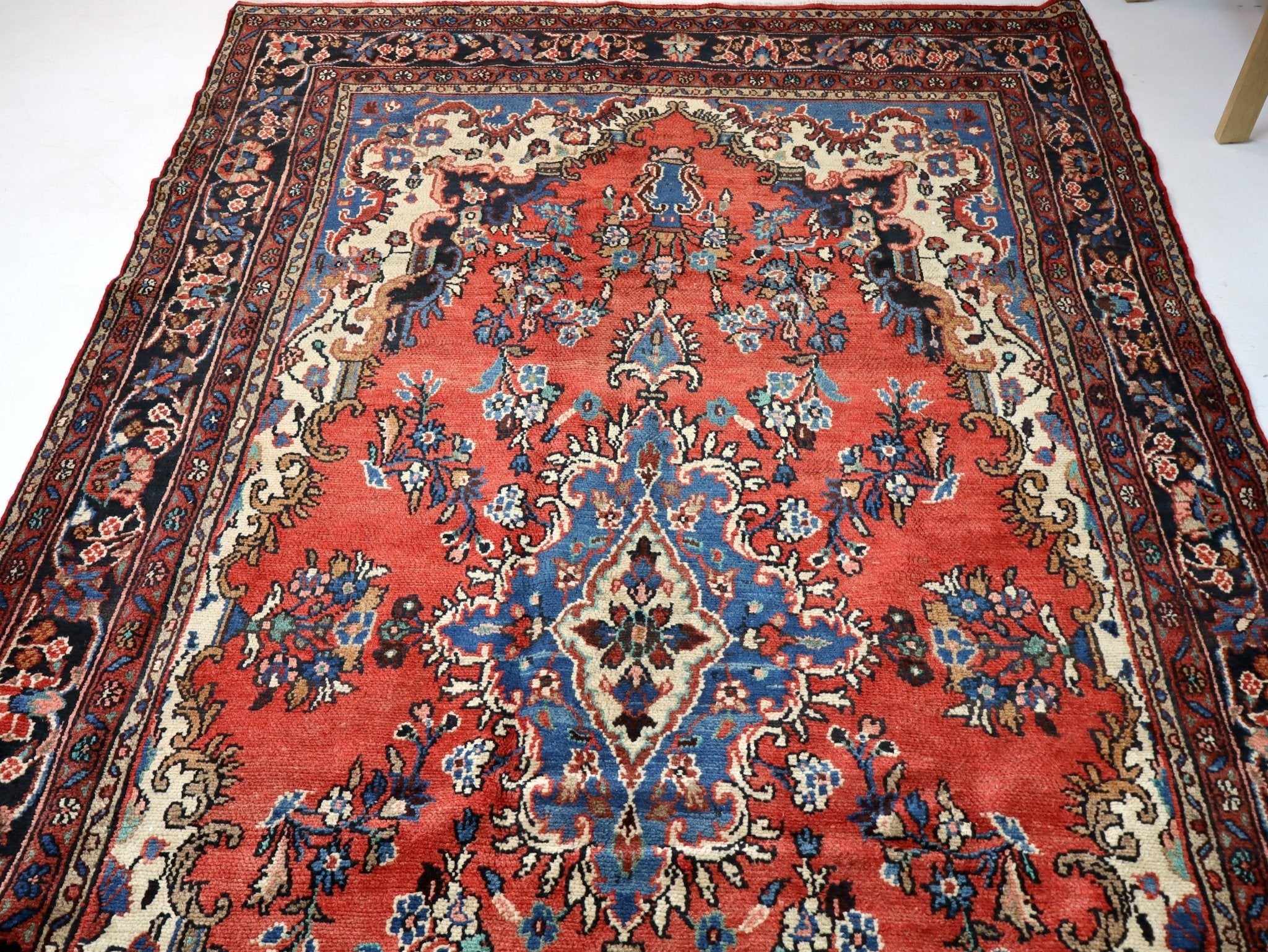 Persian rug close-up: central medallion in rust red with blue floral sprays