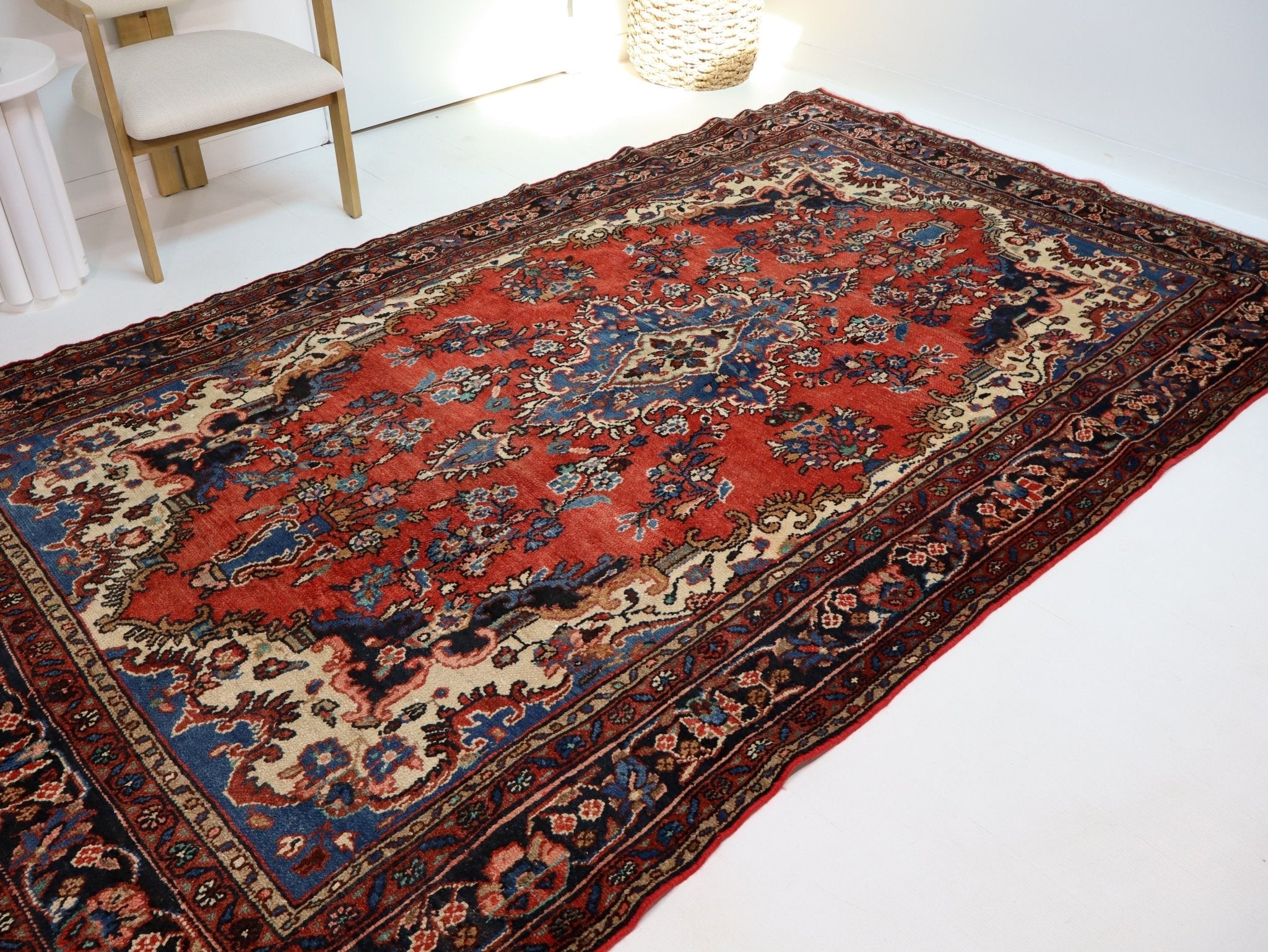 Persian rug laid flat, rust red center with navy-and-cream ornamental border