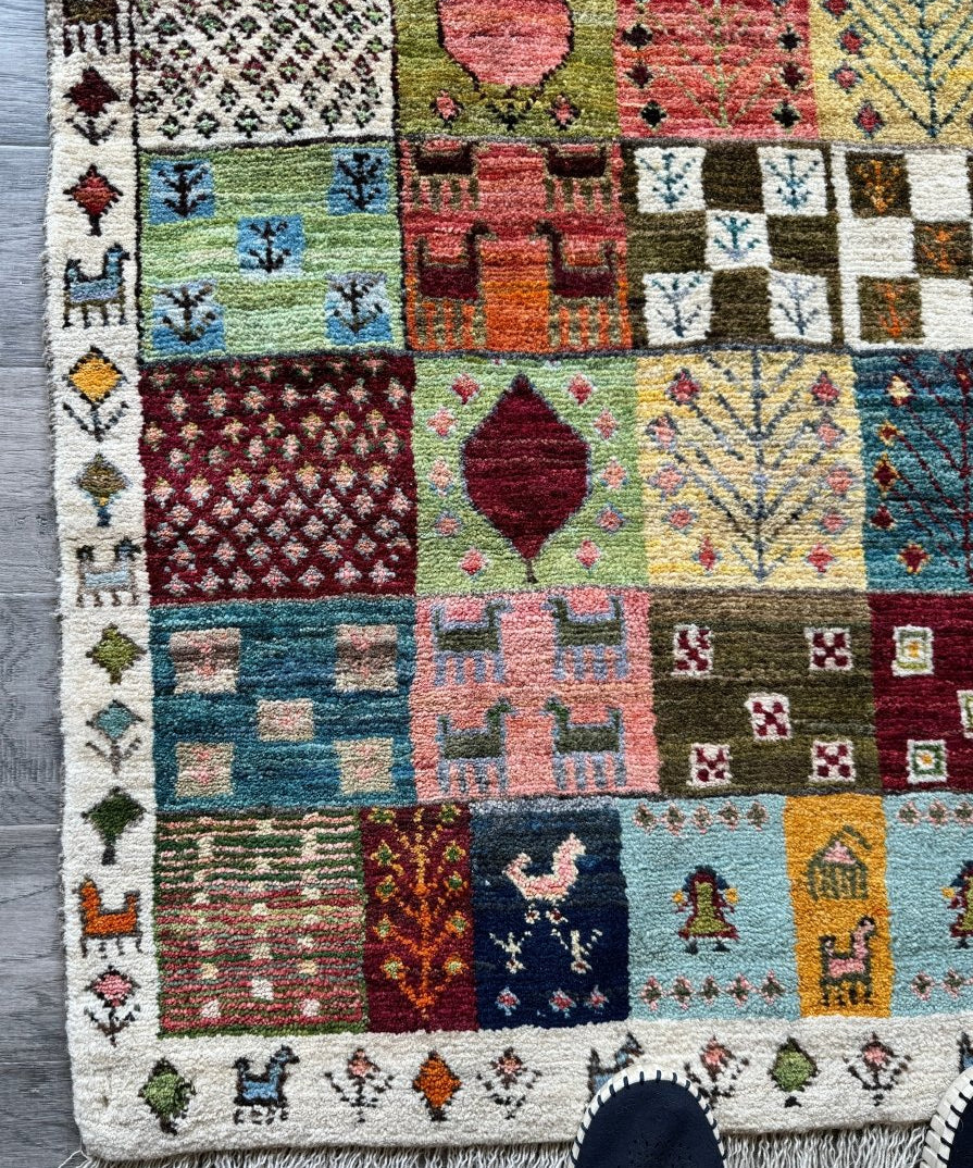 Persian Gabbeh rug with multicolor geometric blocks, diamonds, and borders on cream ground