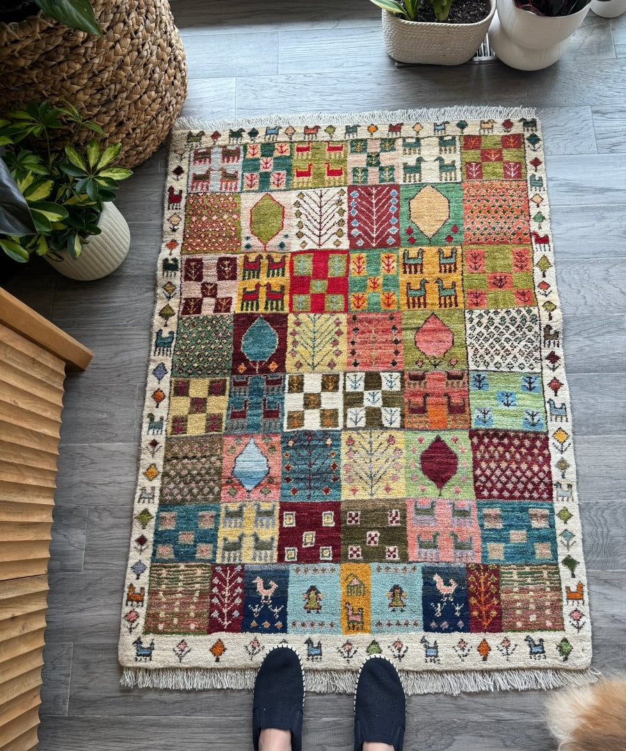 Small Persian Gabbeh rug featuring colorful geometric patches, hearts, trees, and fringe trim