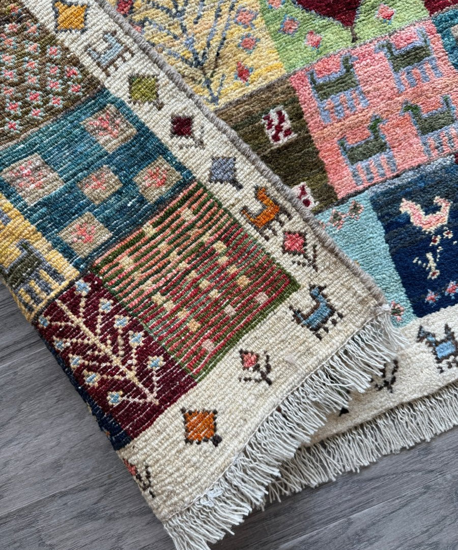 Close-up Persian Gabbeh rug corner with woven geometric motifs and short fringed border
