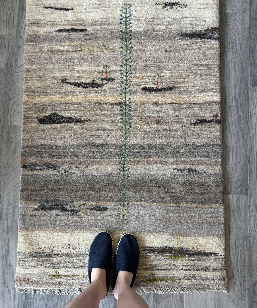Persian Gabbeh rug with beige ground, gray stripes, central green-blue motif, fringed edges