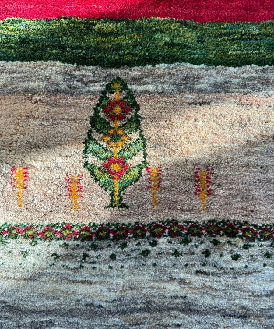 Persian Gabbeh rug close-up with central tree medallion, multicolor flowers, and dark border