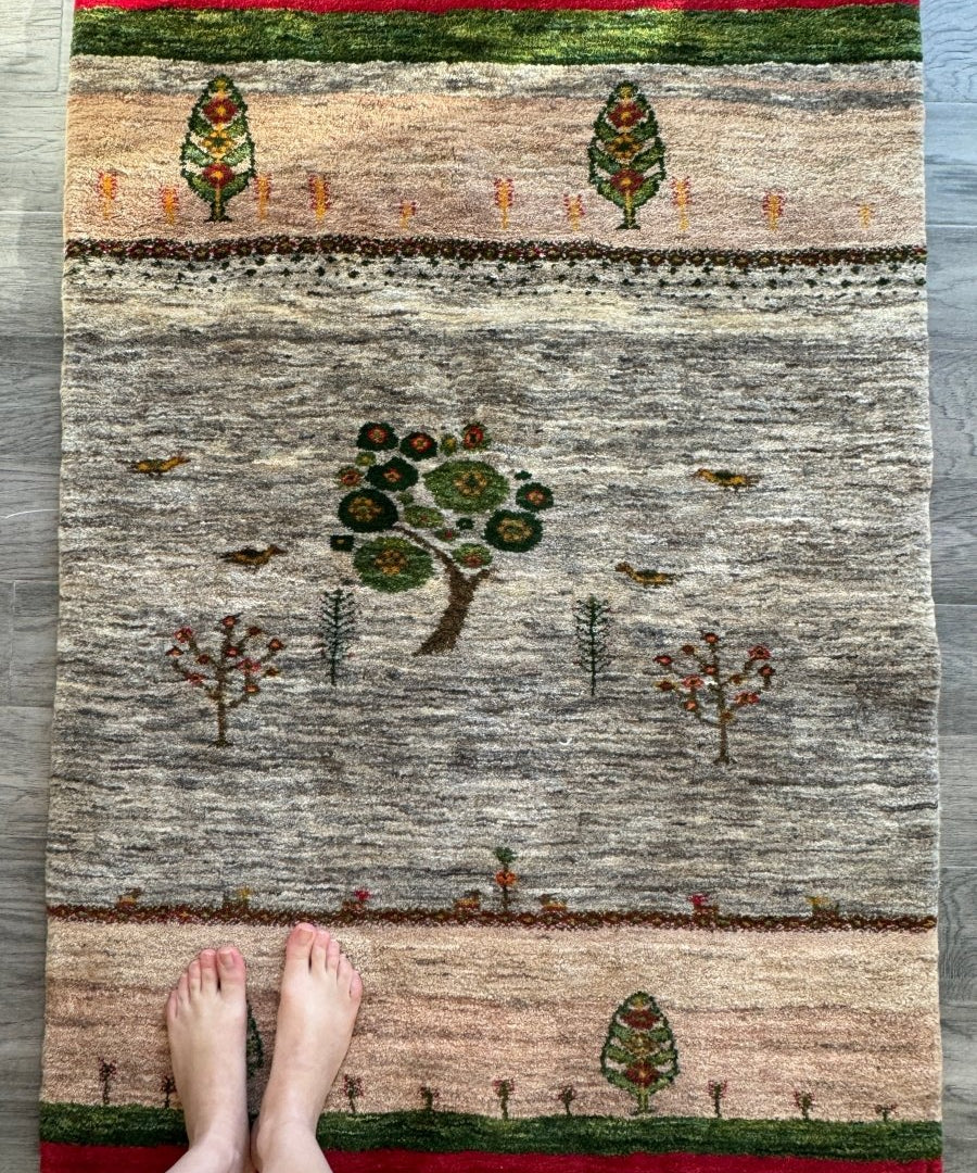 Persian Gabbeh rug with central tree motif, green and red accents, and red fringe border