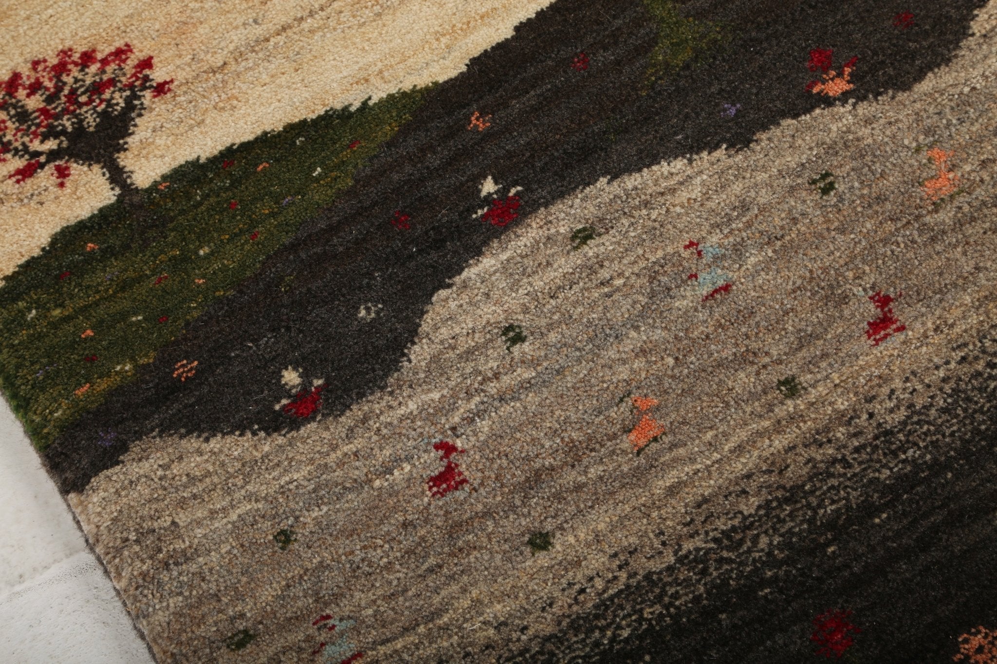 Persian Gabbeh rug close-up with cream top, dark band, and gray field with red flecks