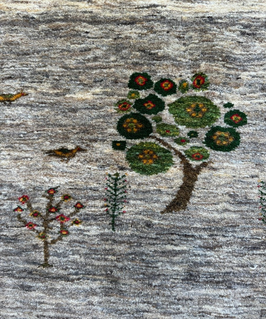 Persian Gabbeh rug featuring central tree design with scattered small flowers on gray field