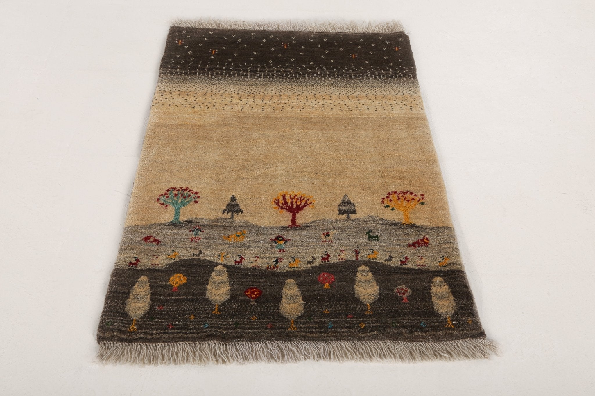 Gabbeh rug with dark top band, beige center, and colorful tree, animal, and figure rows