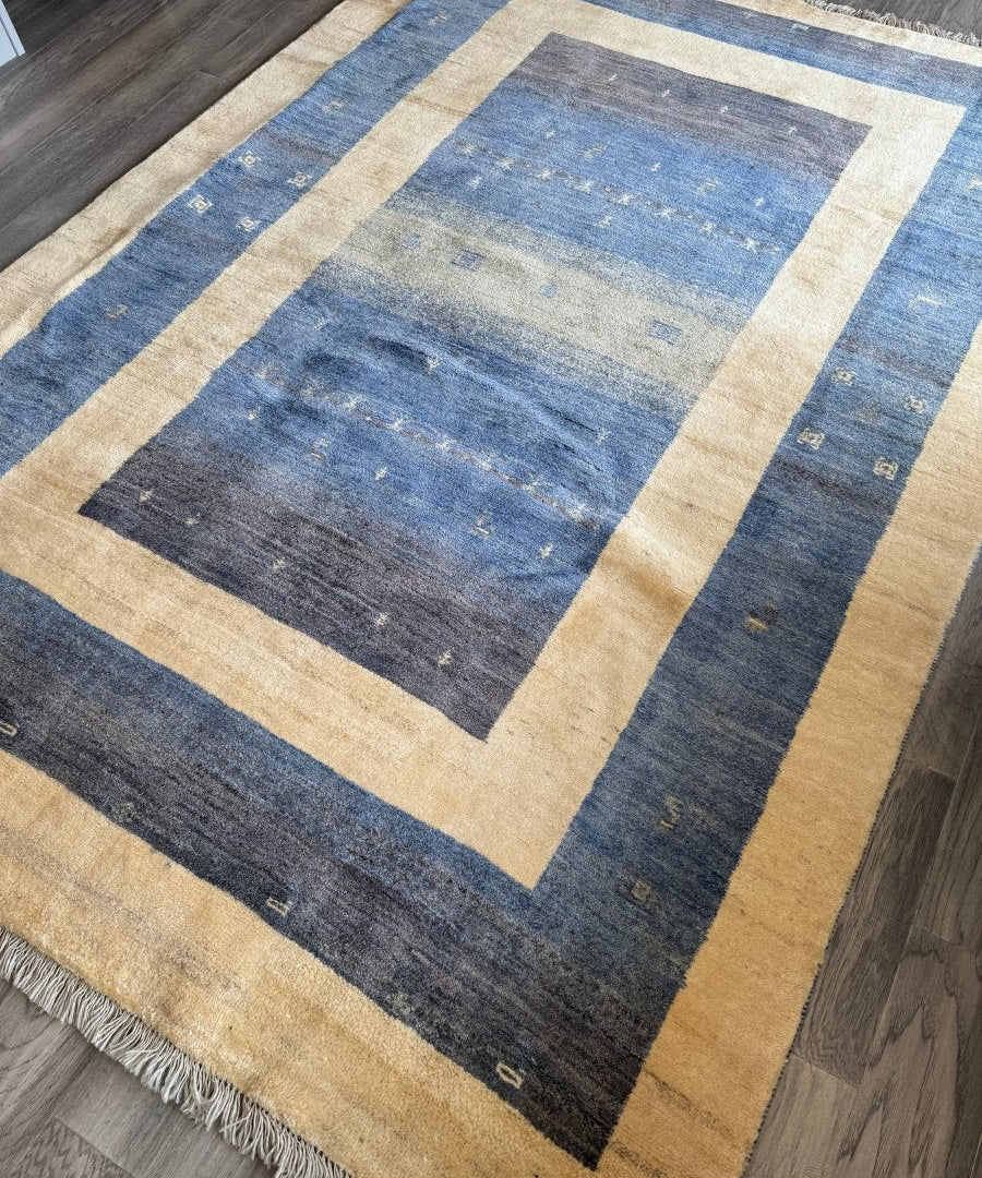 Gabbeh-style rug with blue-gray geometric blocks and wide beige frame, short fringes