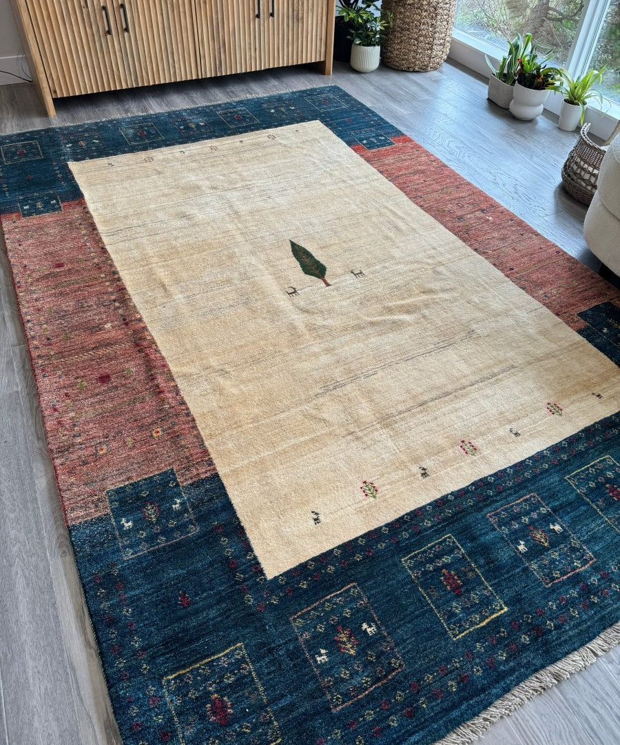 Beige Persian Gabbeh rug with central bird and dark blue red border