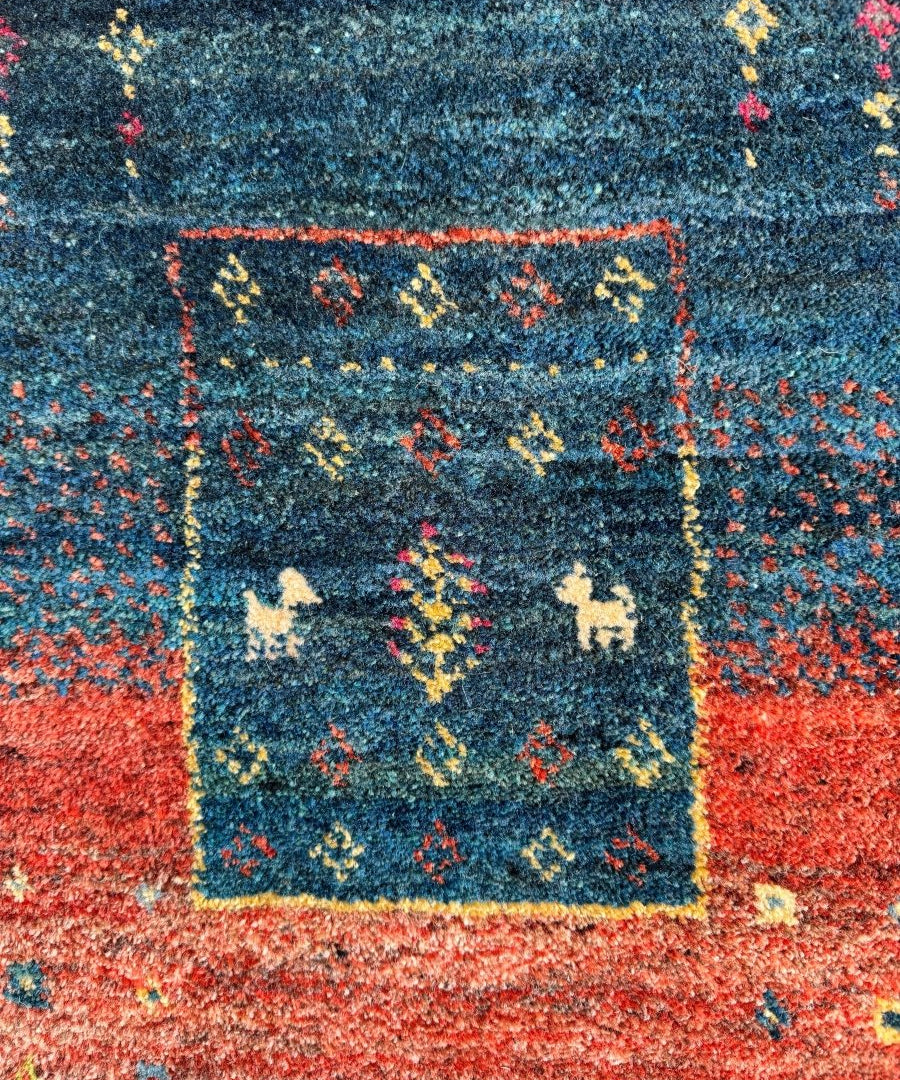 Close-up Persian Gabbeh rug with blue field, red speckle, cream motif