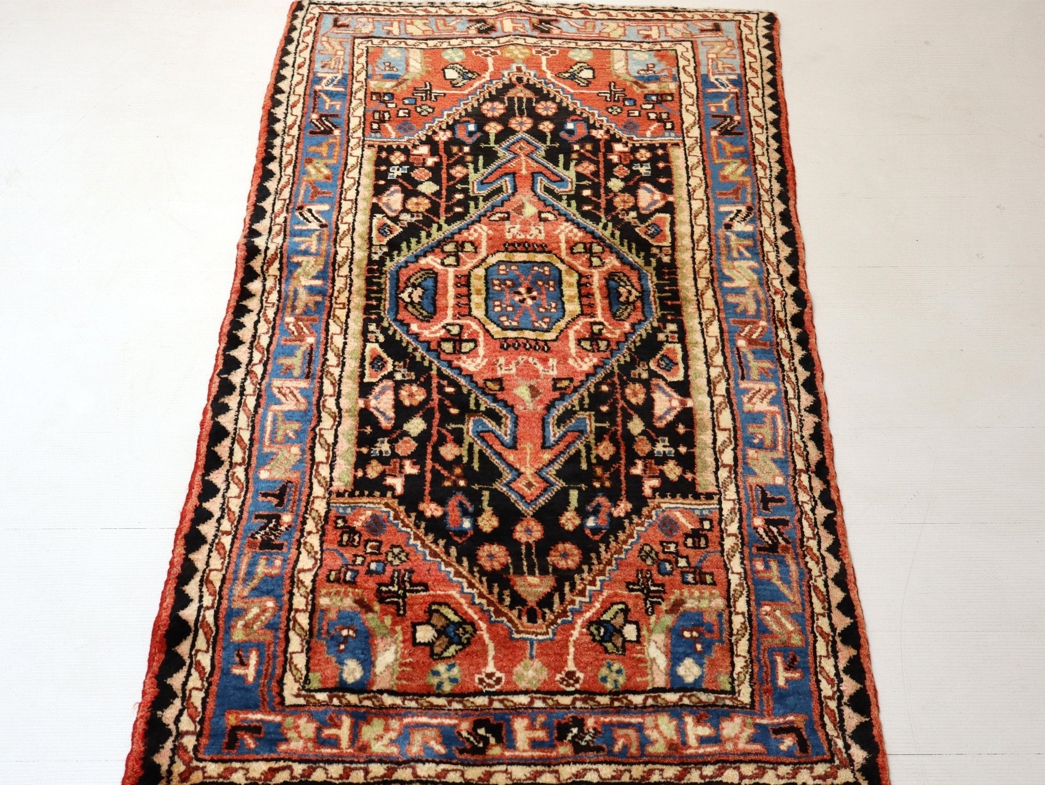 Persian Hamadan rug full view with black field, red accents, and blue border