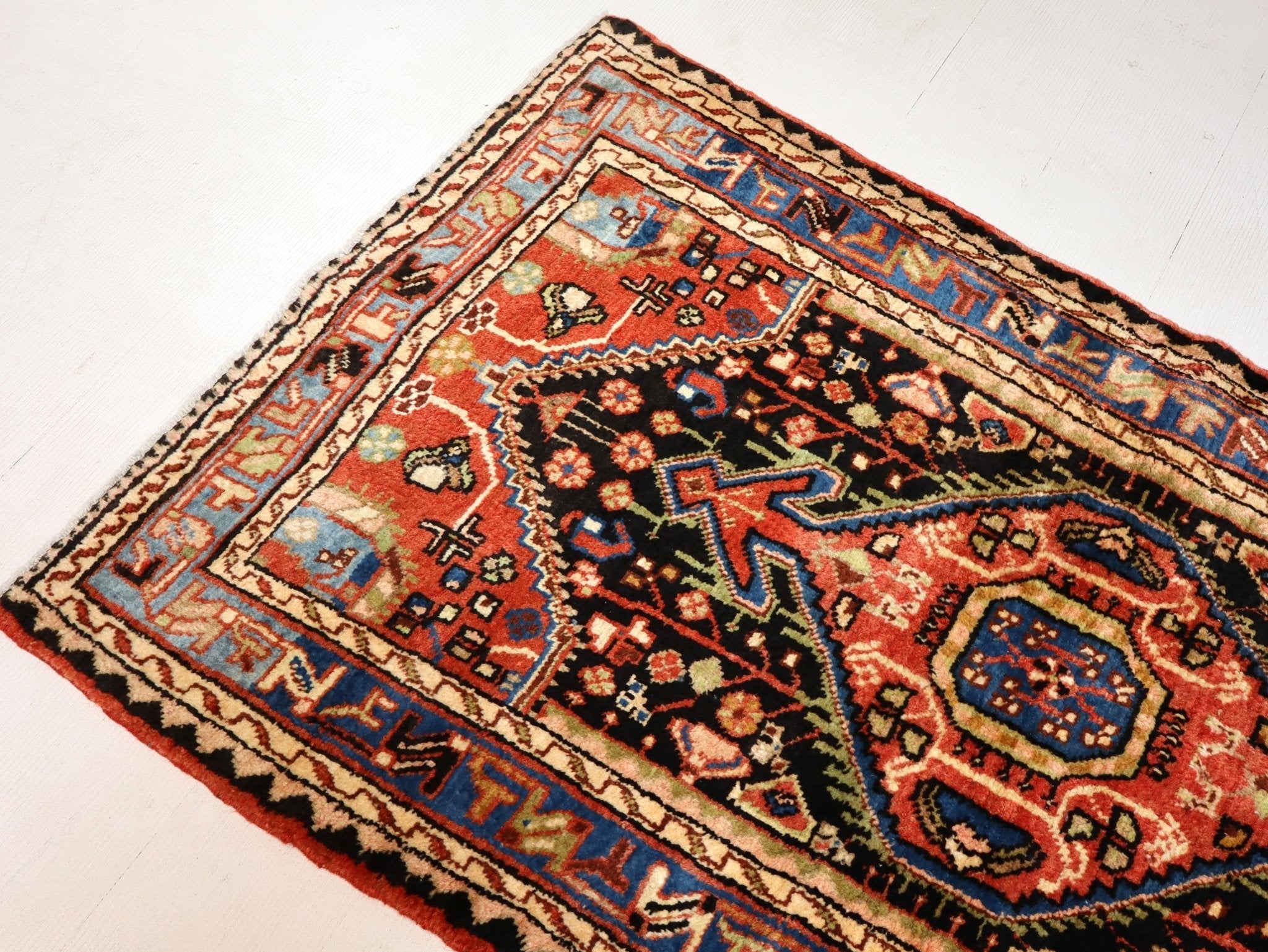 Persian Hamadan rug diagonal view with orange-red field and blue corner motifs