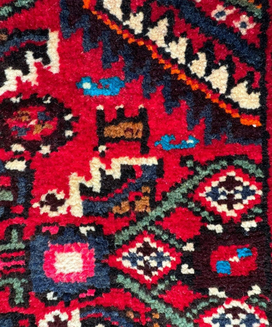 Navy, red, and white rug detail with diamond shapes and stepped geometric bands.