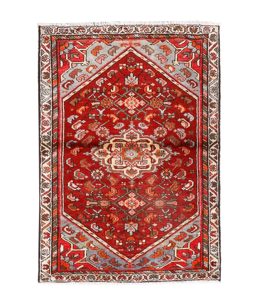 Red Persian-style area rug on white background, cream medallion and intricate geometric border.