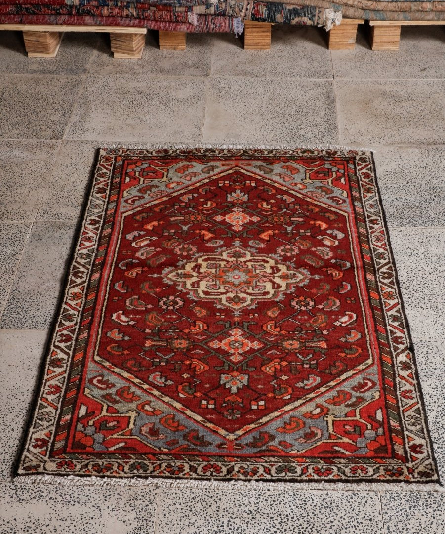 Red Persian-style area rug with cream medallion and geometric border, dark accents.