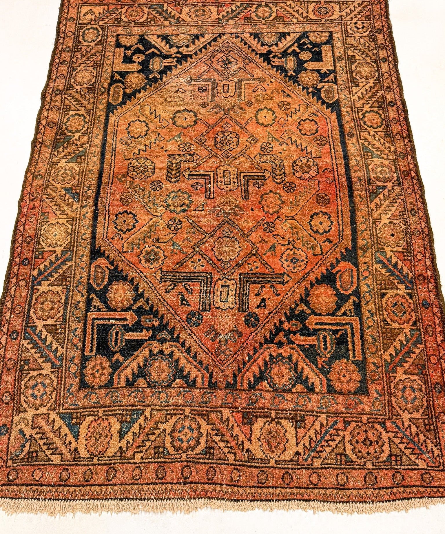 Hamadan rug with rust orange central medallion, dark border, and short fringe