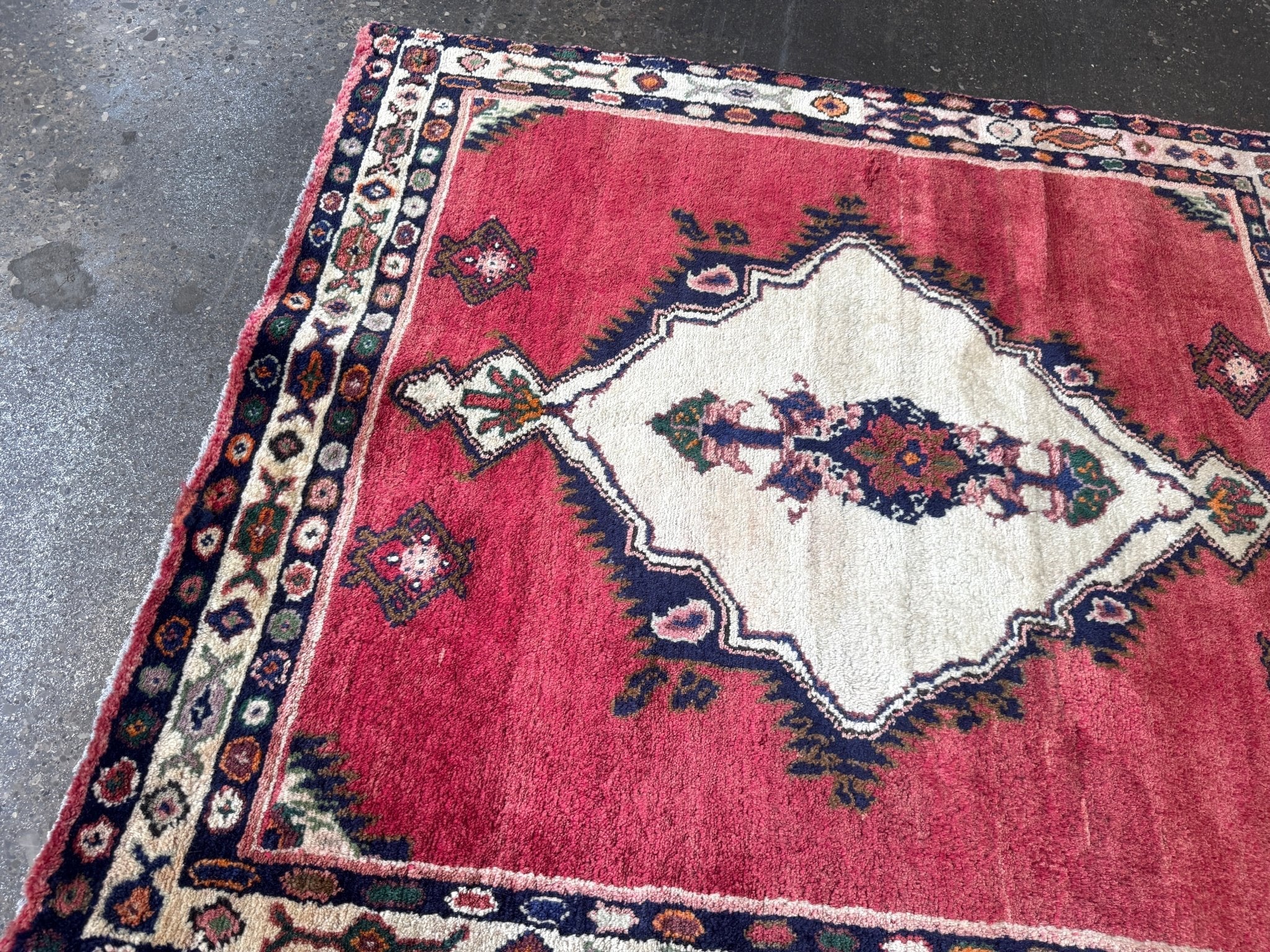 Small Persian-style area rug with red field, cream medallion, navy border