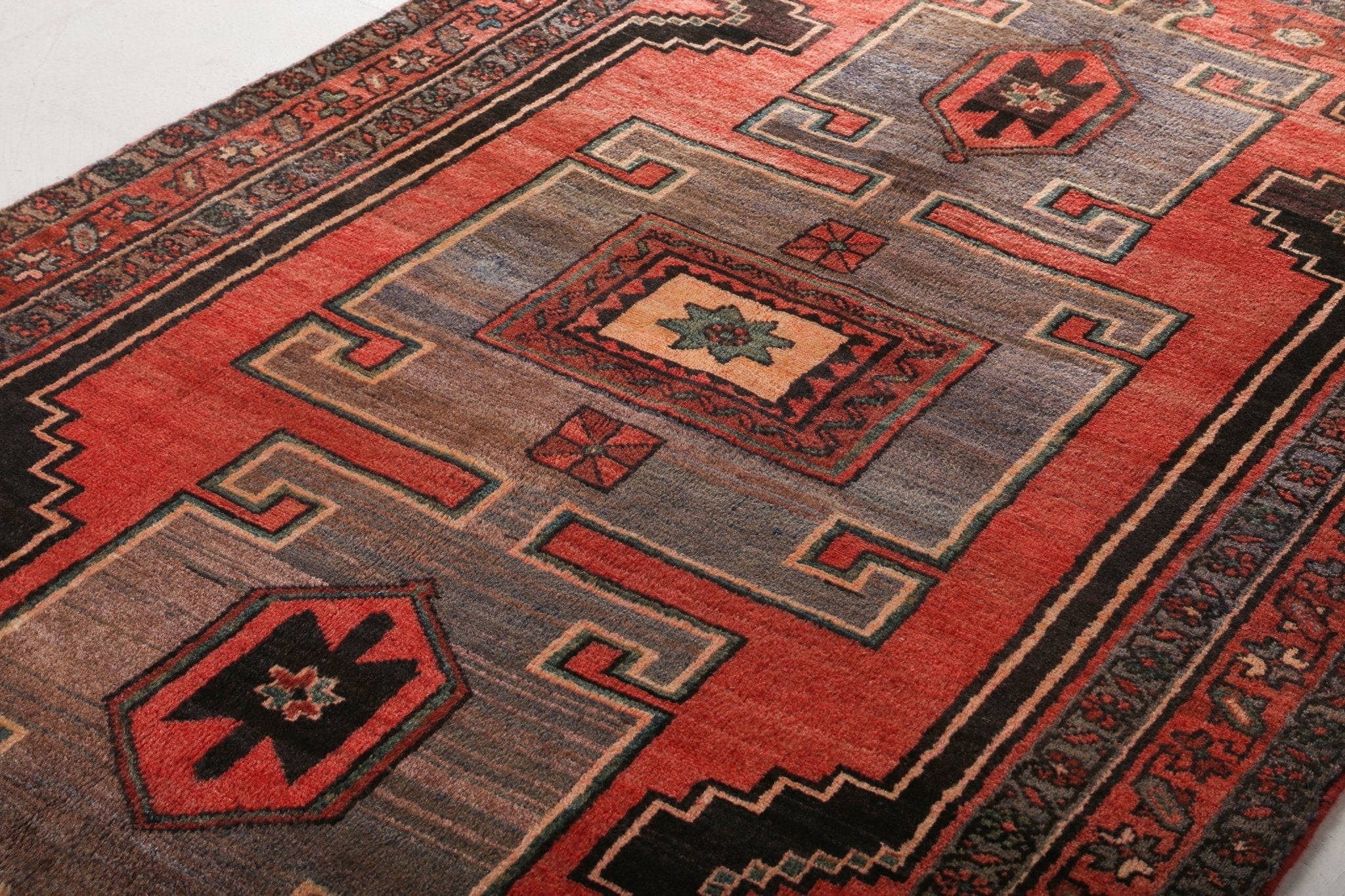 Persian Hamadan rug close-up of red and gray field with geometric medallions