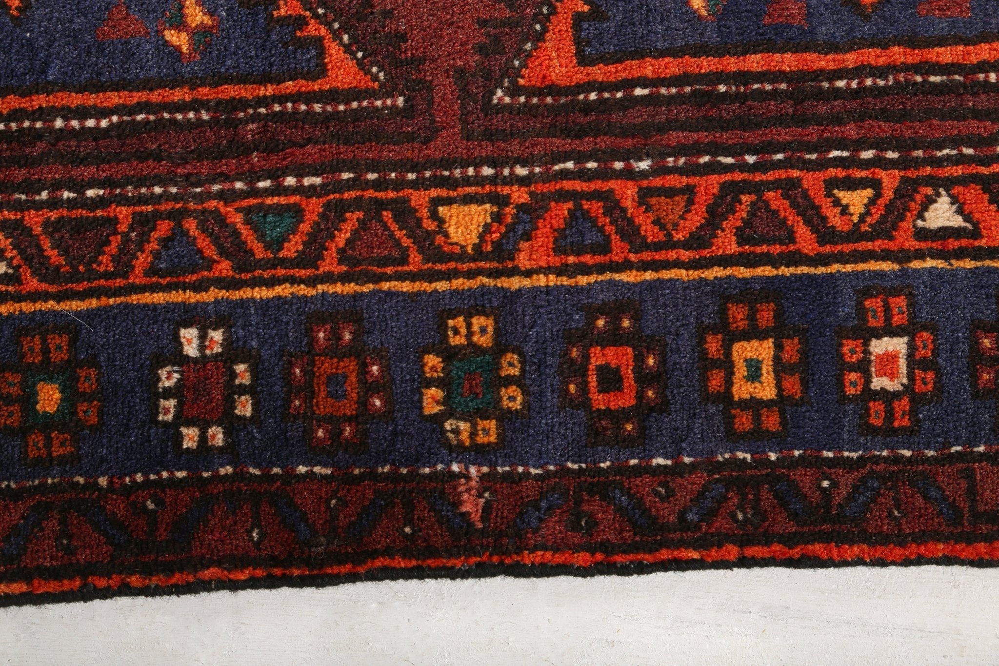 Hamadan Persian rug border close-up with repeating navy and rust small square motifs