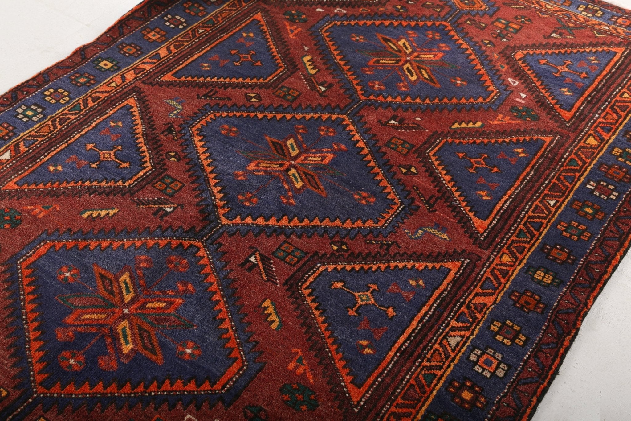 Persian Hamadan rug with red field and navy geometric medallions, zigzag border