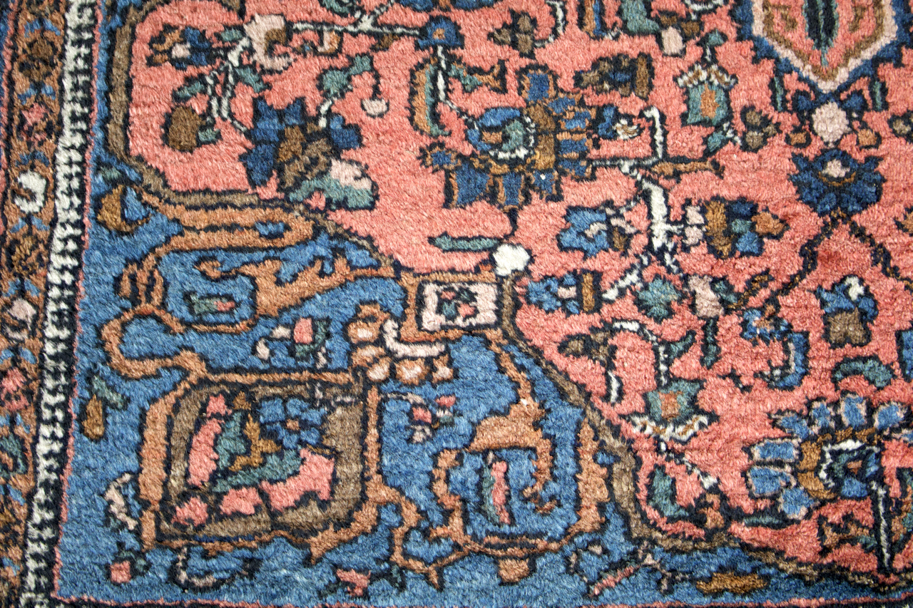 Hamadan-style Persian rug close-up of pink field with blue vine and floral motifs.