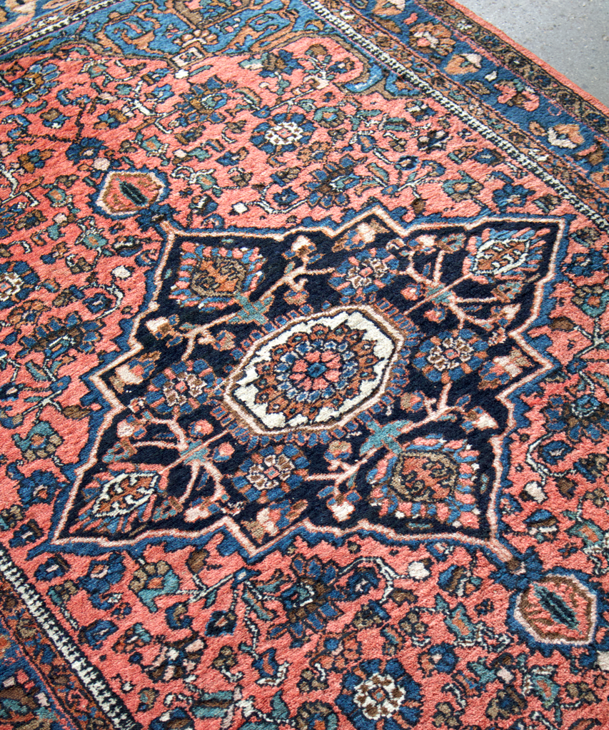 Persian Hamadan rug angled view with central medallion and rust-blue field