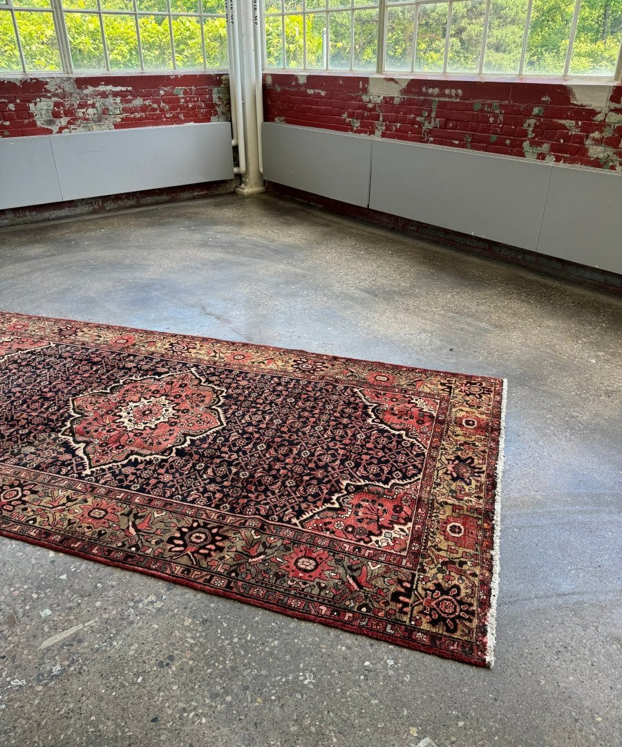 Persian Hamadan rug on floor, navy field with red corner accents and floral center